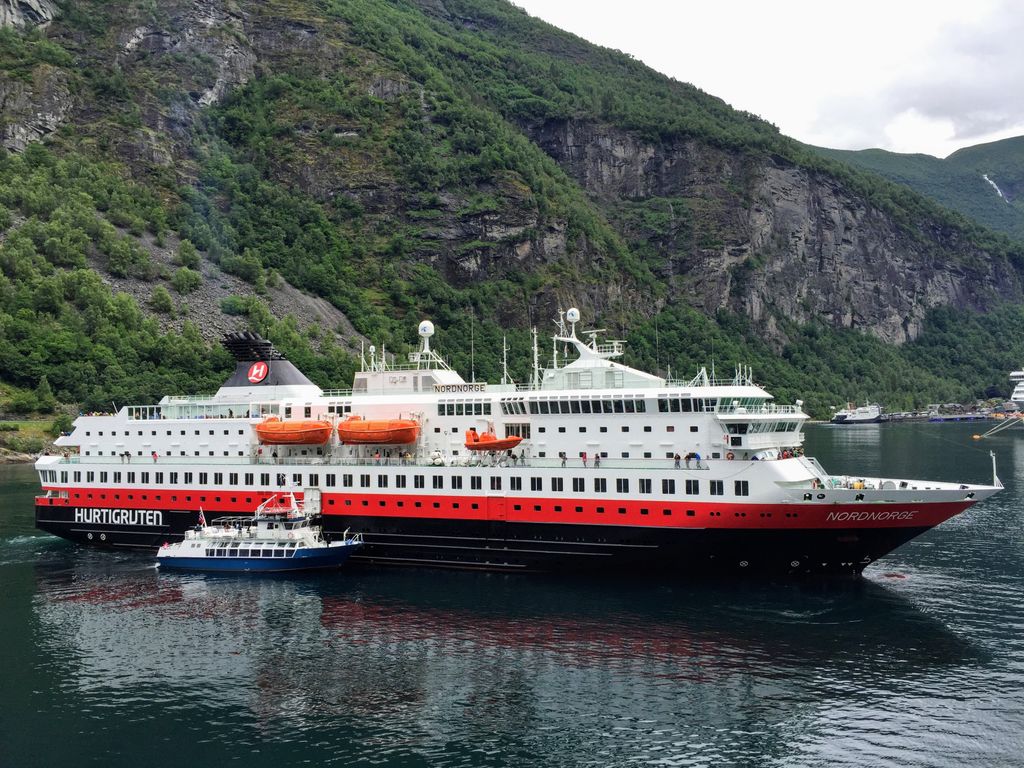 A large red and white cruise ship sailing through a scenic fjord in Møre og Romsdal, Norway.