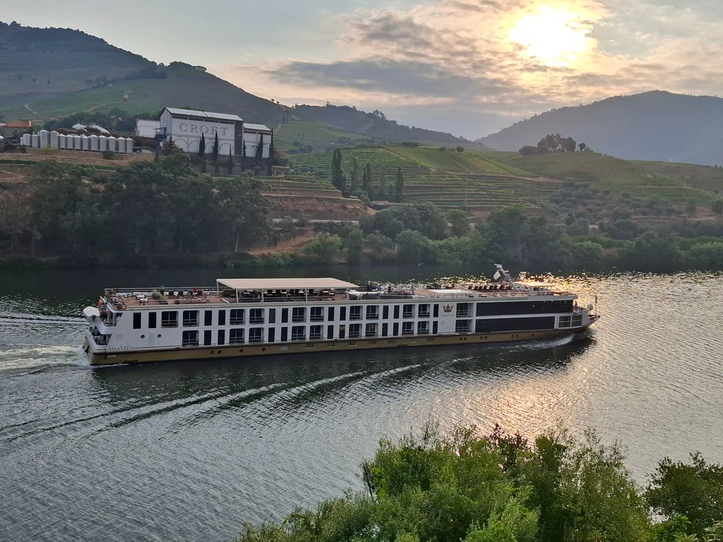 River cruise ship sailing on Douro River, Portugal at sunset.